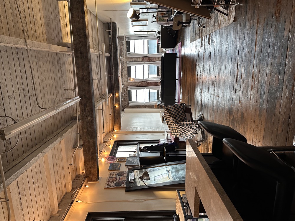 The loft seen from the bar, with wood beams overhead and windows at the far end