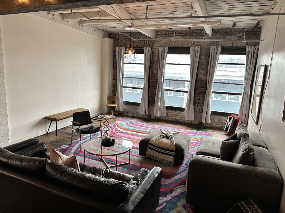 Lounge area under the beams, with windows along the brick wall